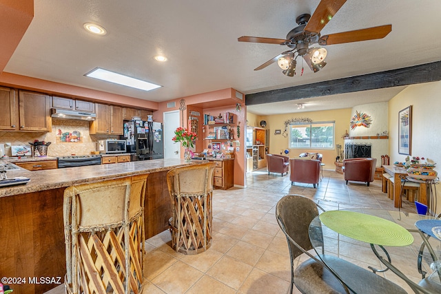 kitchen featuring ceiling fan, beamed ceiling, decorative backsplash, light tile patterned floors, and appliances with stainless steel finishes