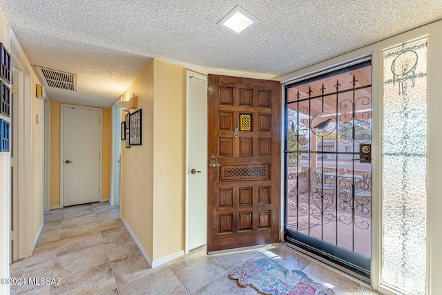 entrance foyer with light tile patterned floors, a textured ceiling, and a wealth of natural light