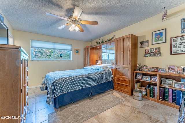 tiled bedroom with ceiling fan and a textured ceiling