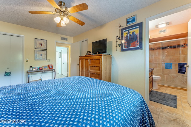 bedroom with connected bathroom, ceiling fan, tile patterned floors, a textured ceiling, and tile walls