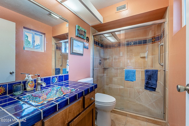 bathroom with tile patterned floors, vanity, a shower with shower door, and toilet