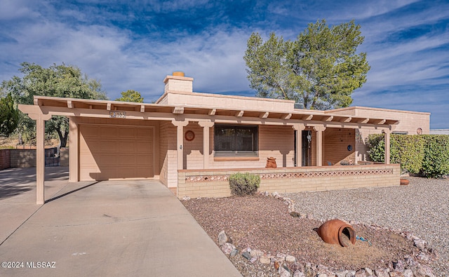 pueblo-style house featuring a porch and a garage