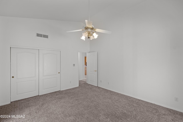 unfurnished bedroom with carpet floors, a closet, high vaulted ceiling, and ceiling fan