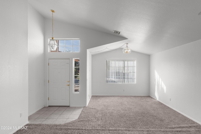 carpeted entryway featuring a textured ceiling, an inviting chandelier, and lofted ceiling