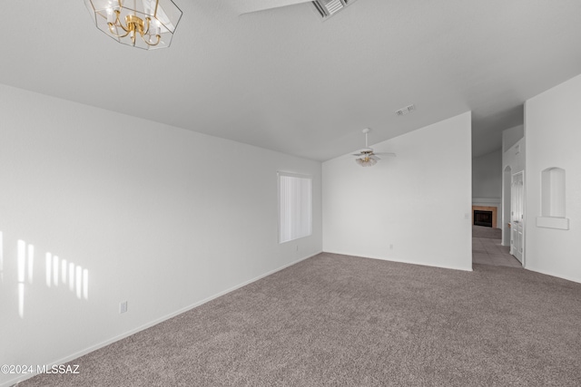 spare room featuring light carpet, ceiling fan with notable chandelier, and a tile fireplace