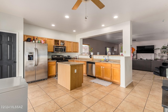 kitchen with ceiling fan, light tile patterned floors, a kitchen island, light stone counters, and stainless steel appliances