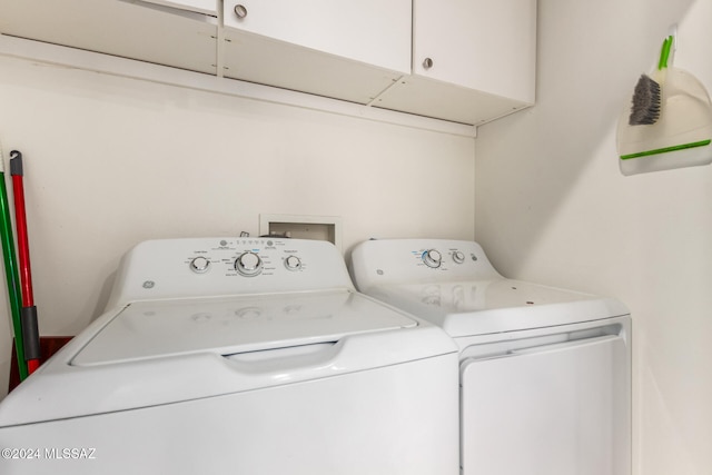 clothes washing area featuring separate washer and dryer and cabinets