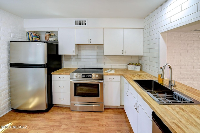 kitchen with wooden counters, sink, light hardwood / wood-style flooring, appliances with stainless steel finishes, and white cabinetry