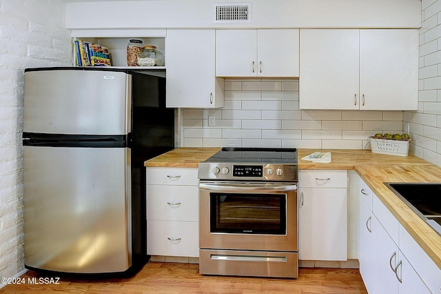 kitchen with white cabinetry, butcher block counters, appliances with stainless steel finishes, and light hardwood / wood-style flooring