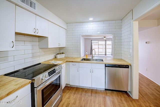 kitchen featuring appliances with stainless steel finishes, light wood-type flooring, and white cabinetry