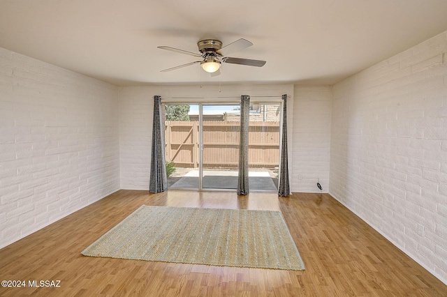 spare room with ceiling fan, brick wall, and light hardwood / wood-style flooring