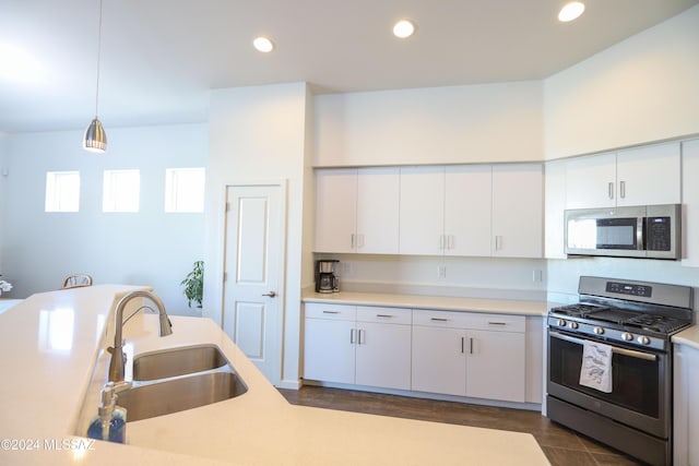 kitchen with white cabinets, appliances with stainless steel finishes, hanging light fixtures, and sink