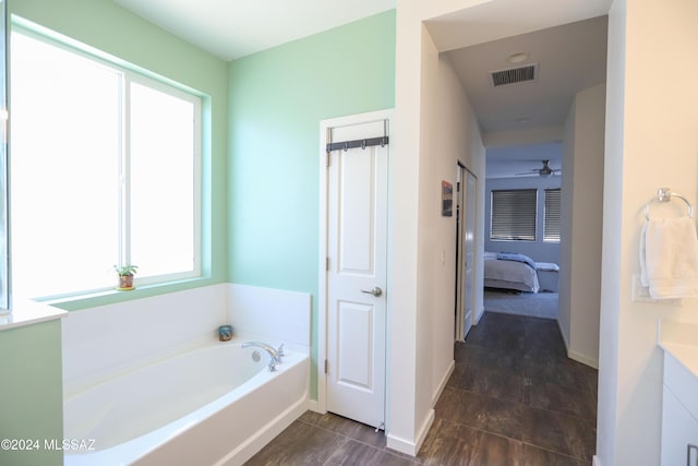 bathroom with ceiling fan, a washtub, and vanity