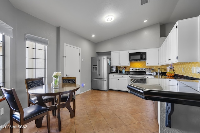 kitchen featuring white cabinetry, tasteful backsplash, vaulted ceiling, light tile patterned floors, and stainless steel appliances