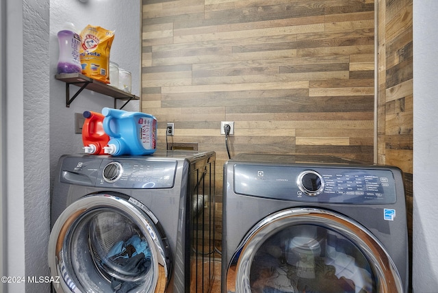 laundry room with washer and dryer and wood walls