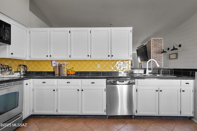 kitchen featuring white cabinetry, stainless steel appliances, and dark tile patterned floors