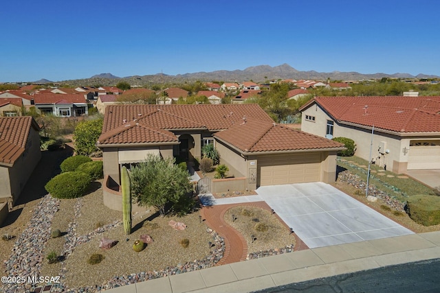 mediterranean / spanish-style home with an attached garage, a tile roof, a residential view, and a mountain view