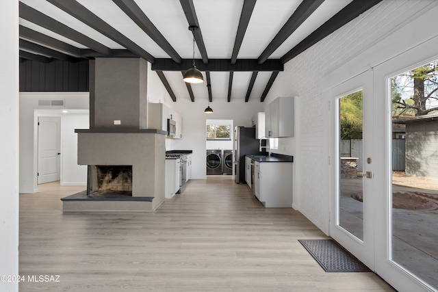 kitchen featuring a wealth of natural light, washer and clothes dryer, appliances with stainless steel finishes, and light hardwood / wood-style flooring