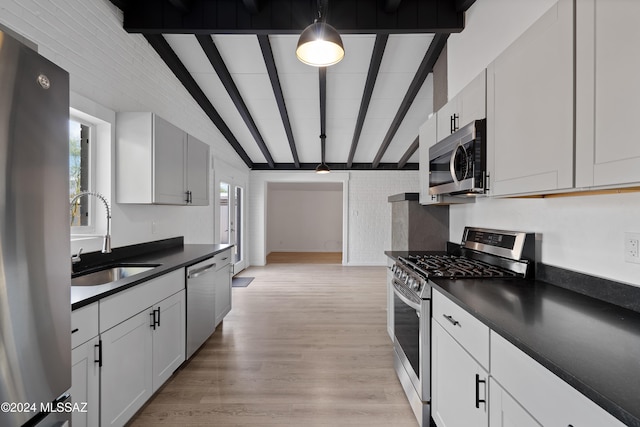 kitchen featuring pendant lighting, lofted ceiling with beams, sink, white cabinetry, and stainless steel appliances