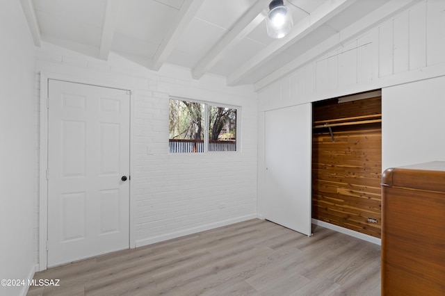 unfurnished bedroom featuring vaulted ceiling with beams, light wood-type flooring, a closet, and ceiling fan