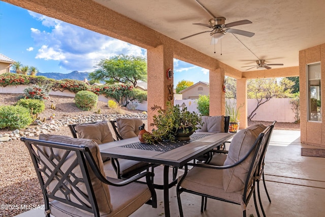 view of patio / terrace with outdoor dining area, ceiling fan, a mountain view, and fence