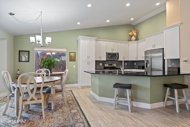 kitchen featuring a chandelier, white cabinetry, stainless steel appliances, and a kitchen breakfast bar