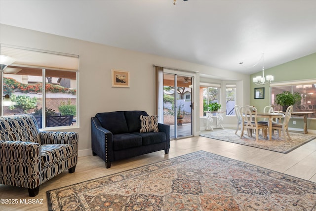 living room with an inviting chandelier, baseboards, lofted ceiling, and wood finished floors