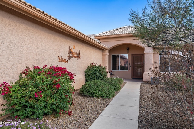 entrance to property featuring stucco siding and a tiled roof