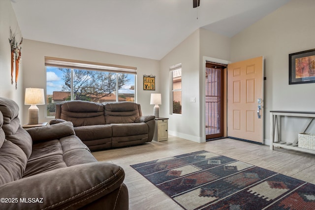 living room featuring high vaulted ceiling, light wood-type flooring, and baseboards