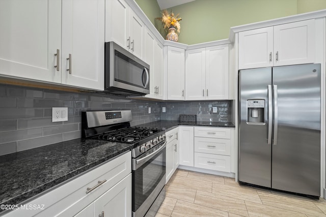 kitchen featuring stainless steel appliances, dark stone counters, tasteful backsplash, and white cabinetry