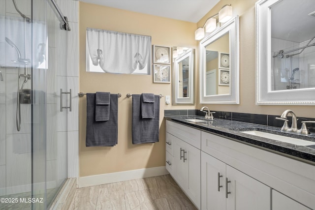 bathroom with a shower stall, double vanity, and a sink