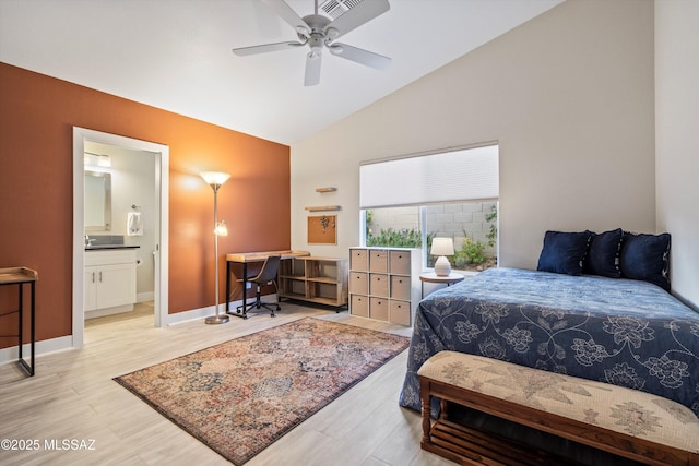 bedroom with ceiling fan, baseboards, lofted ceiling, light wood-style floors, and ensuite bath