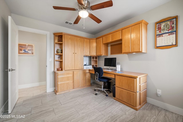 office with visible vents, baseboards, ceiling fan, and built in desk