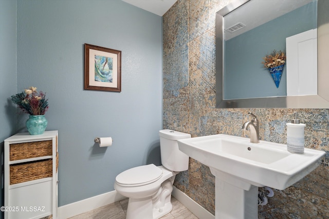 bathroom featuring toilet, baseboards, visible vents, and backsplash