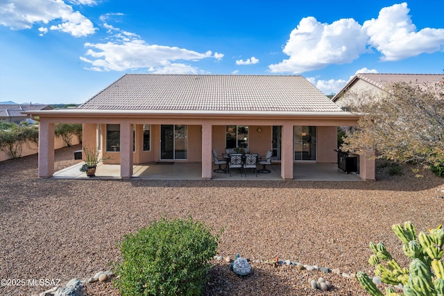 back of house featuring a tile roof, a patio area, and stucco siding