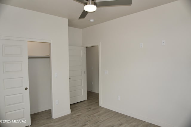 unfurnished bedroom with ceiling fan, light wood-type flooring, and a closet