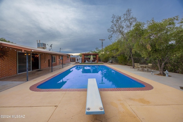 view of pool featuring central AC, a diving board, and a patio area