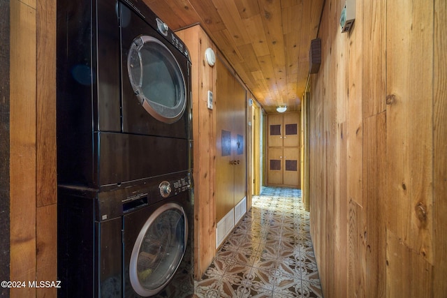 washroom featuring stacked washer / dryer, wood walls, and wooden ceiling