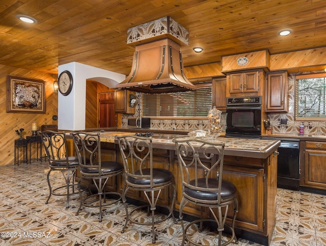 1440 W Roller Coaster Rd, Tucson, AZ 85704 - kitchen featuring black appliances, wooden walls, tasteful backsplash, tile countertops, and a breakfast bar