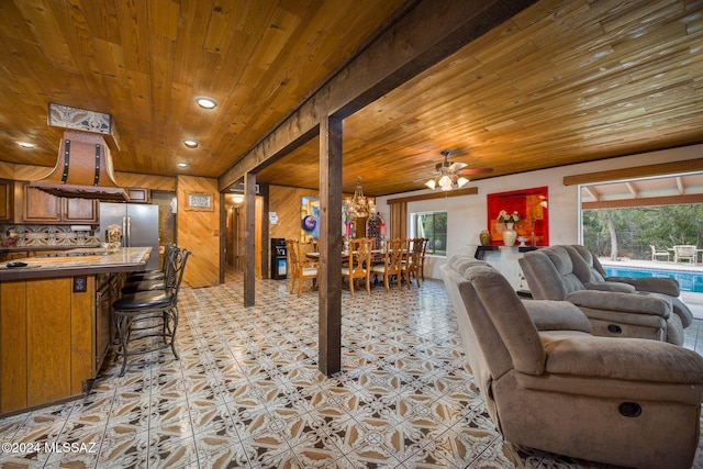 living room with ceiling fan, wood ceiling, and wood walls