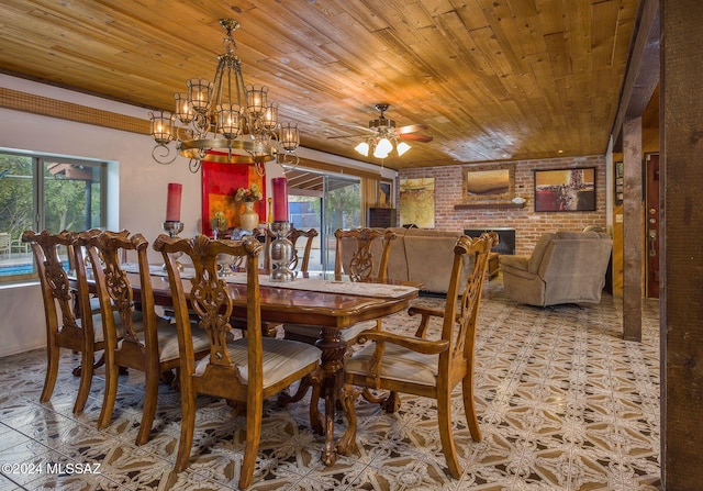 dining space featuring plenty of natural light, brick wall, ceiling fan with notable chandelier, and a brick fireplace