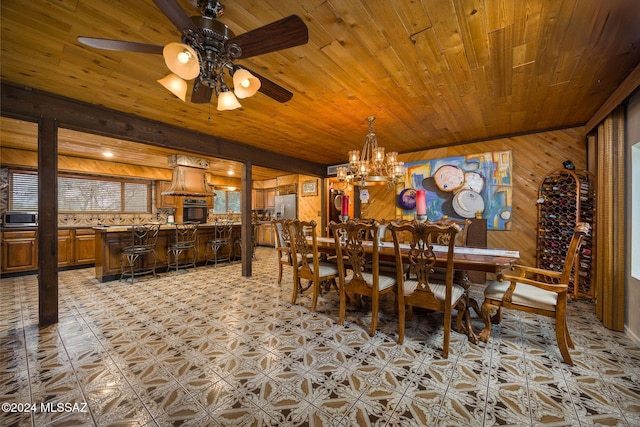 dining room with ceiling fan with notable chandelier, wooden ceiling, and wooden walls