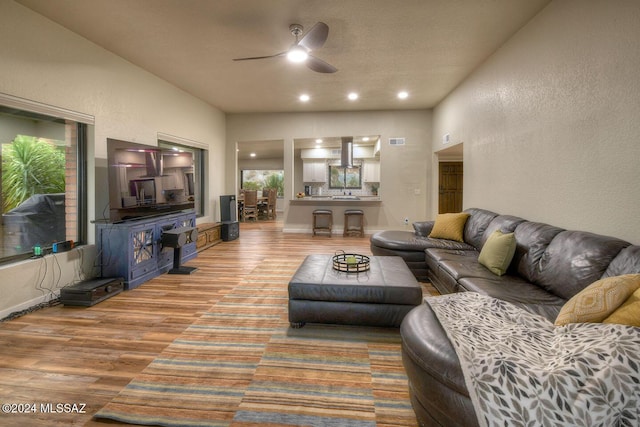 living area with visible vents, ceiling fan, wood finished floors, recessed lighting, and a textured wall