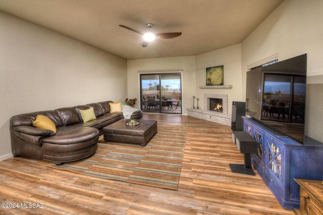 living room with a textured ceiling, ceiling fan, and light hardwood / wood-style floors