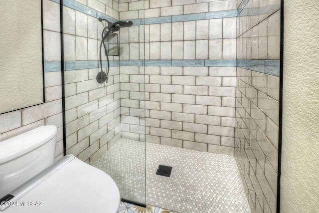 bathroom featuring tiled shower and toilet