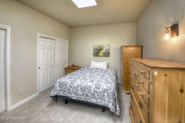 bedroom with a skylight, light carpet, and a closet