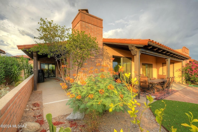 exterior space featuring a tile roof, a patio area, and a chimney