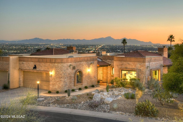 view of front facade with an attached garage, a mountain view, and driveway