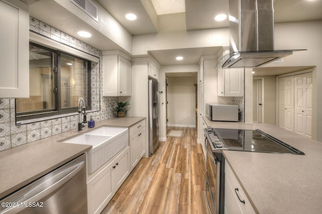 kitchen with sink, white cabinetry, stainless steel appliances, island range hood, and light hardwood / wood-style floors