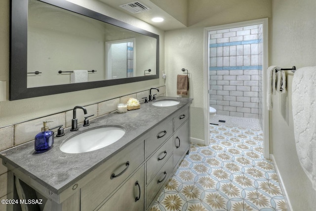 bathroom with vanity, toilet, tile patterned flooring, and backsplash